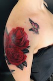 Realistisches Rosen Schmetterling Tattoo auf dem Oberarm.